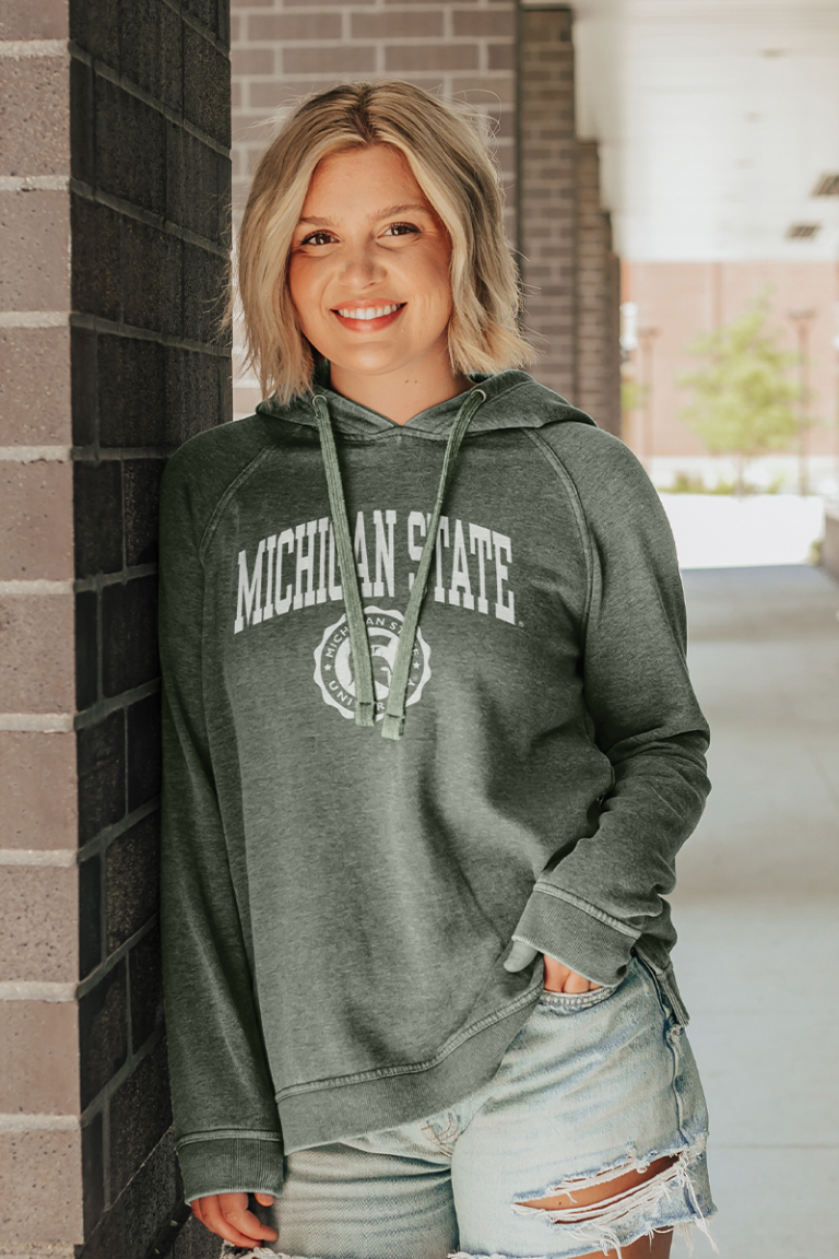 Female model wearing a college Blue 84 hooded sweatshirt.
